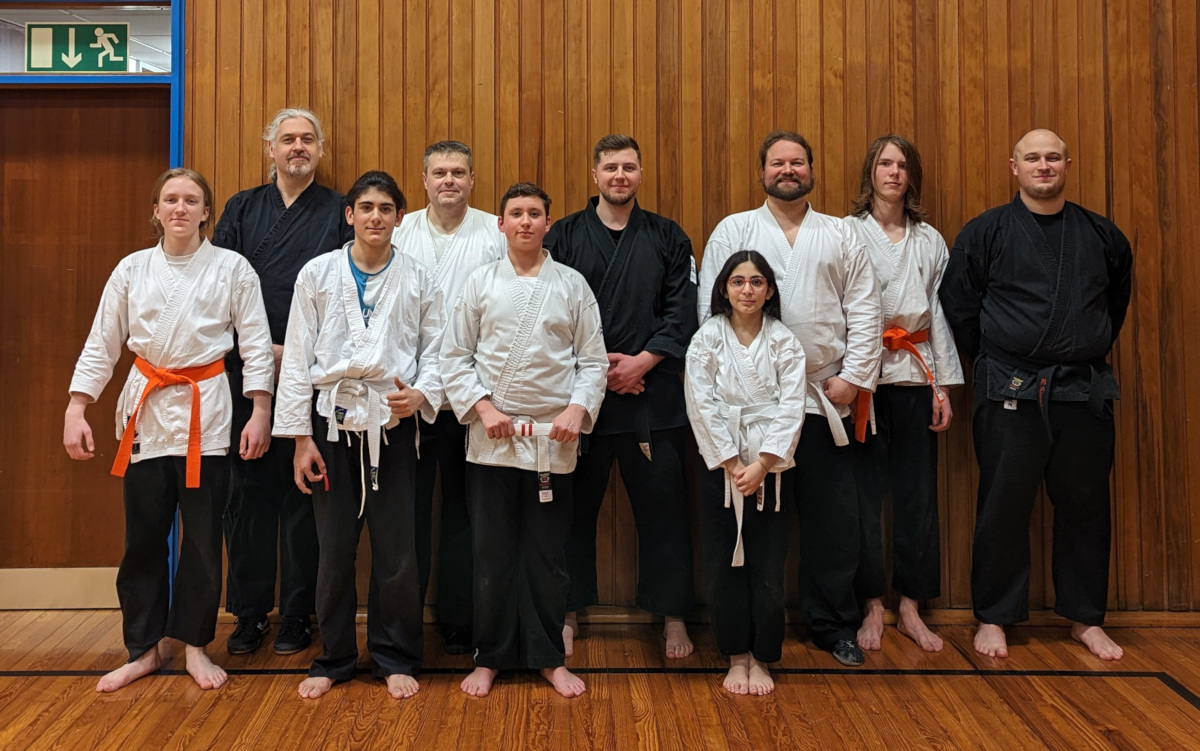 Zwei Reihen von Shaolin-Kempo-Sportlern. Trainer in Schwarz, Schüler in schwarzer Hose und weißer Jacke.